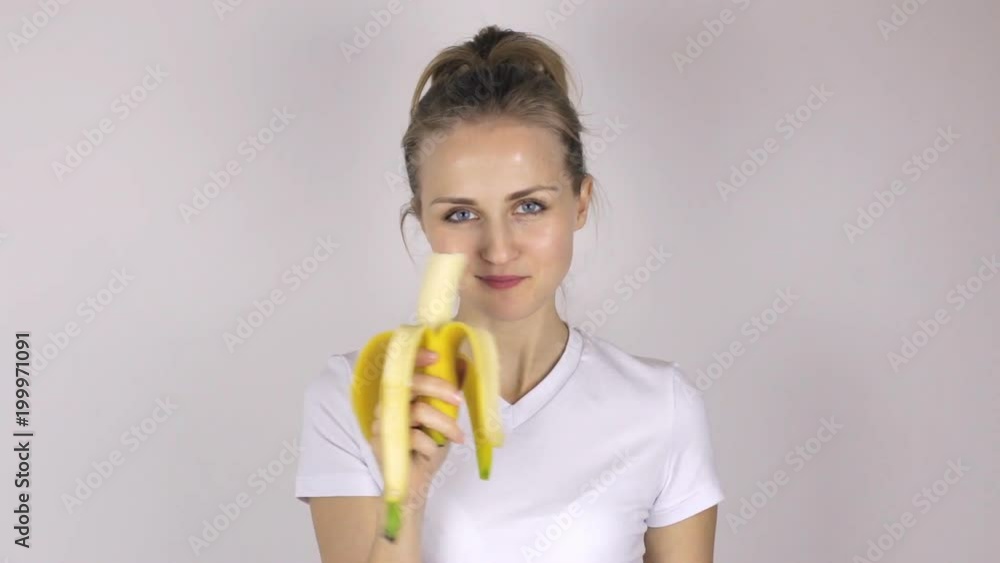 Beautiful young woman eats banana and showing thumb up. Close-up Beautiful young woman eats banana and showing thumb up. Close-up