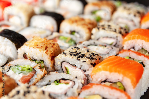 Assorted sushi rolls on black background
