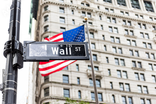 Wall street street sign in New York City NYC Manhattan lower financial district downtown, with American flag, banner, building in background