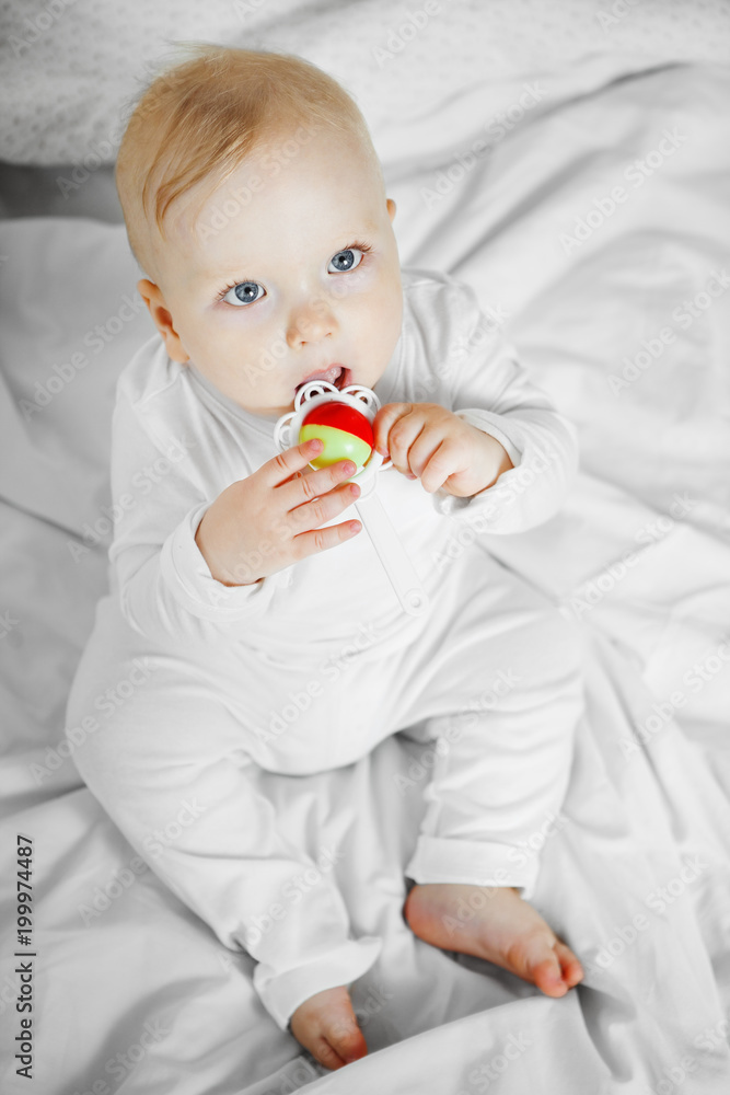 Baby takes rattle in mouth with serious face Baby takes rattle in mouth with serious face