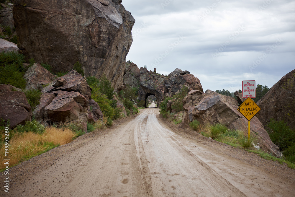 Dirt road along rocks with tunnel