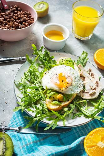 Tasty sandwich with avocado and egg  arugula on concrete background. Delicious breakfast.