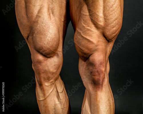 Foto Detail of male bodybuilder front leg muscles on black background