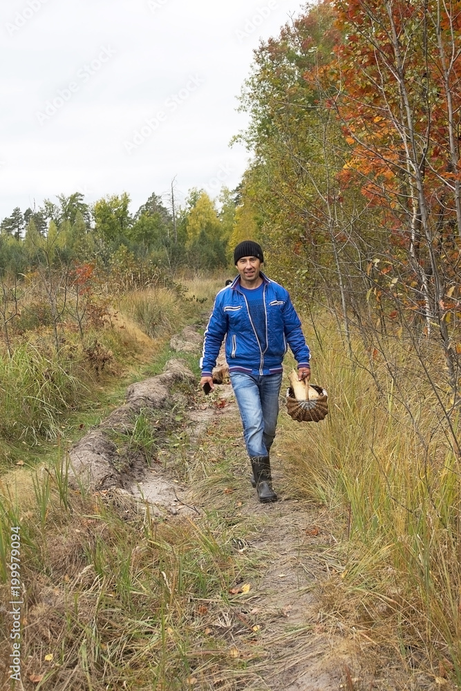 A young man, a forester walks through the forest, collects mushrooms A young man, a forester walks through the forest, collects mushrooms