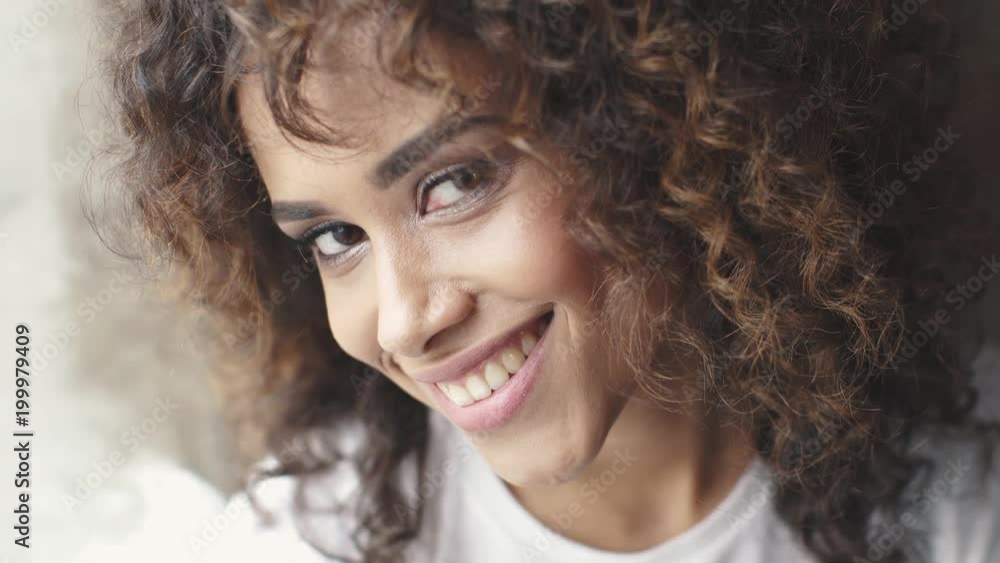 headshot portrait of a attractive hispanic girl with a beautiful smile. girl with brown eyes and curly hair turns and smiles at the camera headshot portrait of a attractive hispanic girl with a beautiful smile. girl with brown eyes and curly hair turns and smiles at the camera