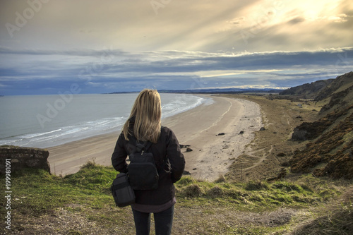 Woman is looking at the seashore. St Cyrus beach, Aberdeenshire, Scotland, UK. 