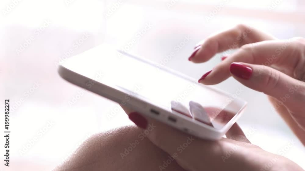The woman sits at a window with the tablet. The woman types in the search box the text on the tablet. The girl thumbs through the text on the tablet. Macro shooting. Female fingers close up. hand The woman sits at a window with the tablet. The woman types in the search box the text on the tablet. The girl thumbs through the text on the tablet. Macro shooting. Female fingers close up. hand