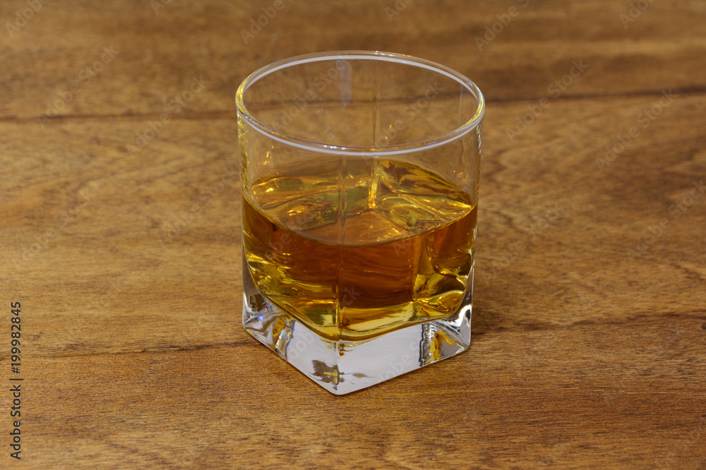 a glass of whiskey on a wooden table top a glass of whiskey on a wooden table top