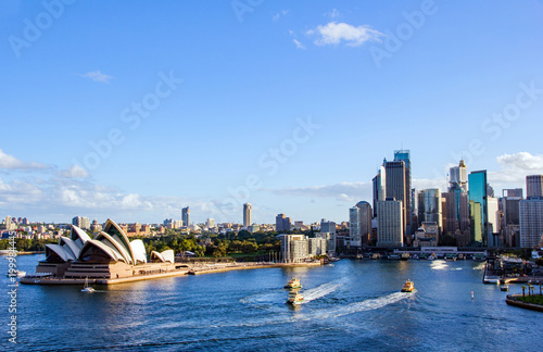 Sydney’s circular quay harbour with multiple ferries arriving and departing and the magnificent backdrop of the quayside and cityscape taken as sun is close to setting © Harry Green