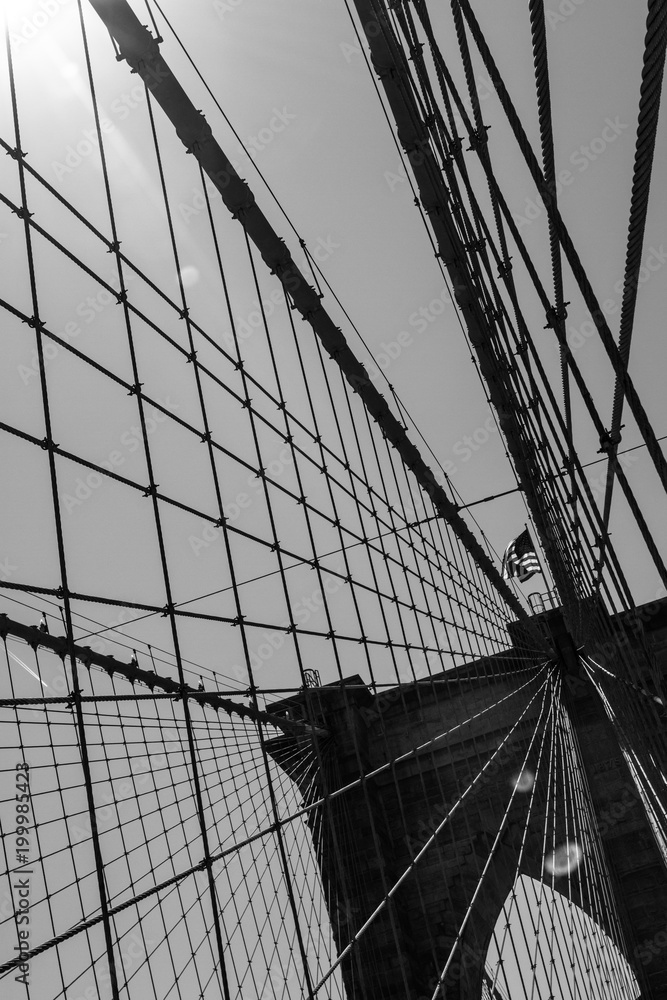 Fototapeta premium Details of the brooklyn bridge and the sun in black and white