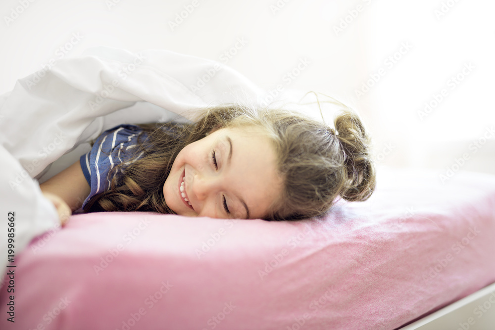 Portrait of a girl under covers by white sheet Portrait of a girl under covers by white sheet