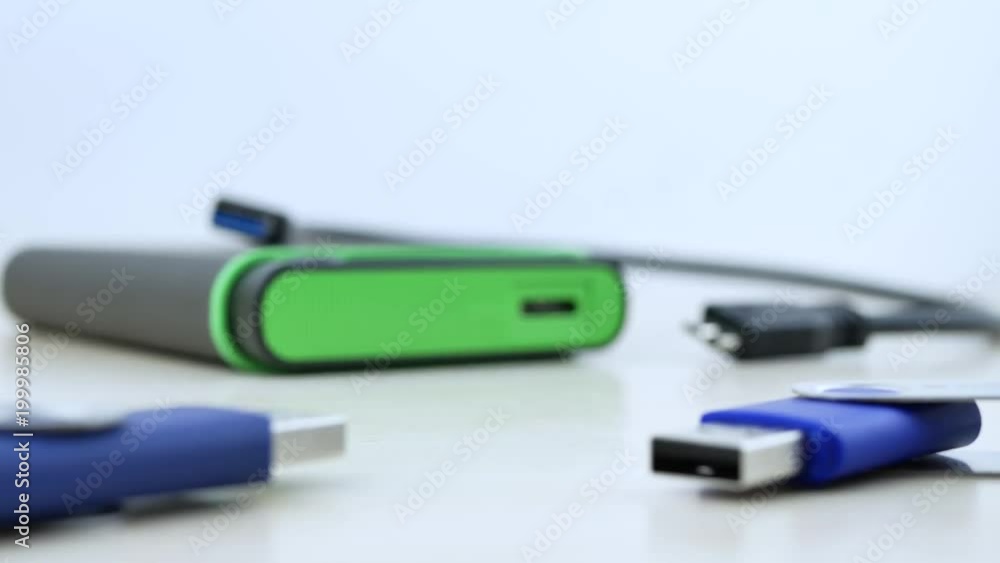 USB Micro B Data Cable with solid state drive SSD and blue USB flash drive on wooden texture office desktop on isoleted white background USB Micro B Data Cable with solid state drive SSD and blue USB flash drive on wooden texture office desktop on isoleted white background