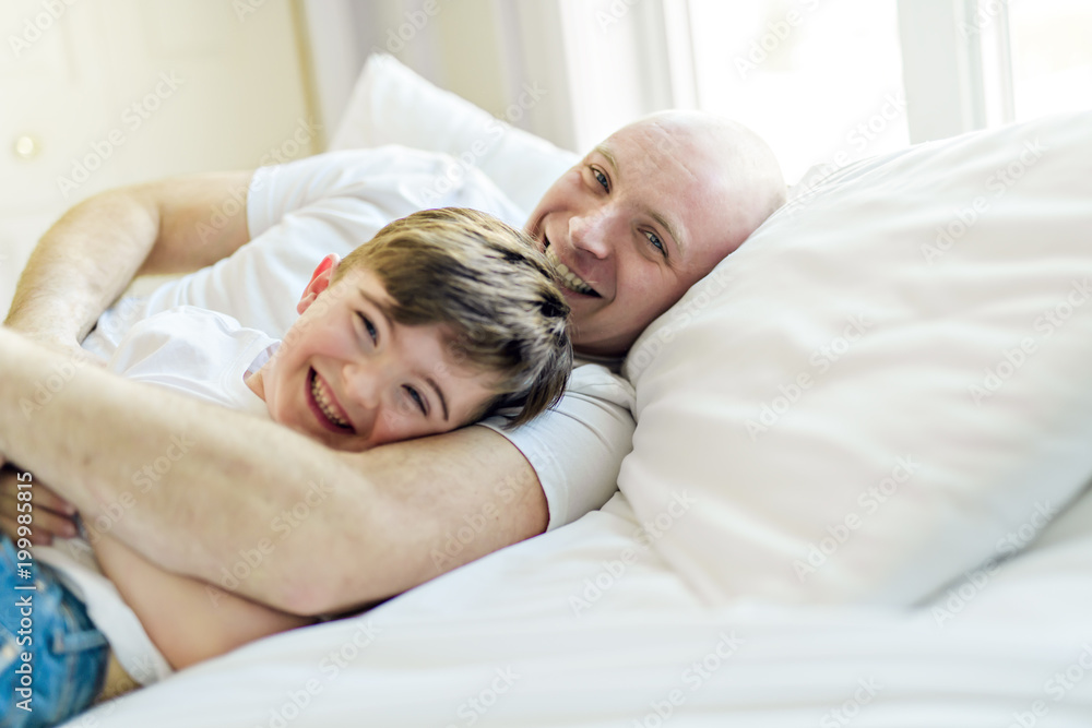 Happy father and son having fun together on a bed Happy father and son having fun together on a bed