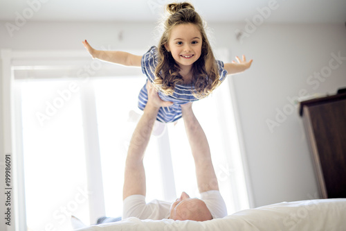 Happy father and daughter having fun together on a bed