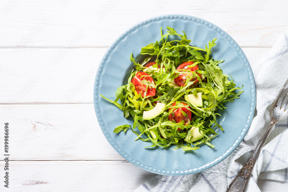 Healthy vegan salad from arugula, avocado and tomatoes. Healthy vegan salad from arugula, avocado and tomatoes.