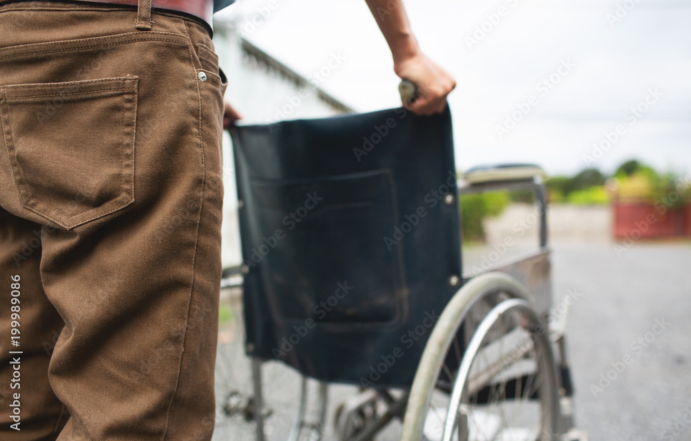Fototapeta premium Close up empty wheelchair with man hands.