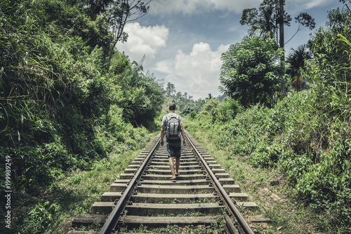 Canvas Print A male tourist walking along the railroad amidst the tropical forest of Sri-Lank