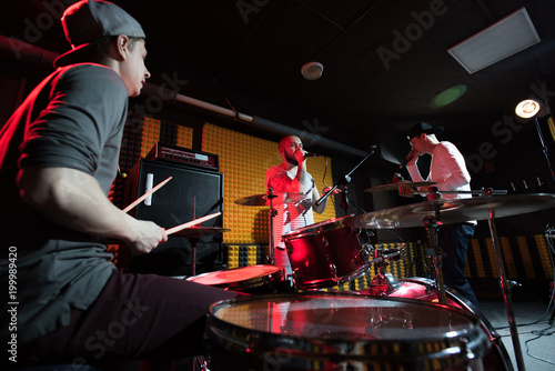 Canvas Print Group of young musicians performing in dim recording studio making new album, dr