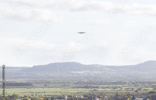 UFO Sighting, flying saucer in the sky over a town, metallic reflective craft