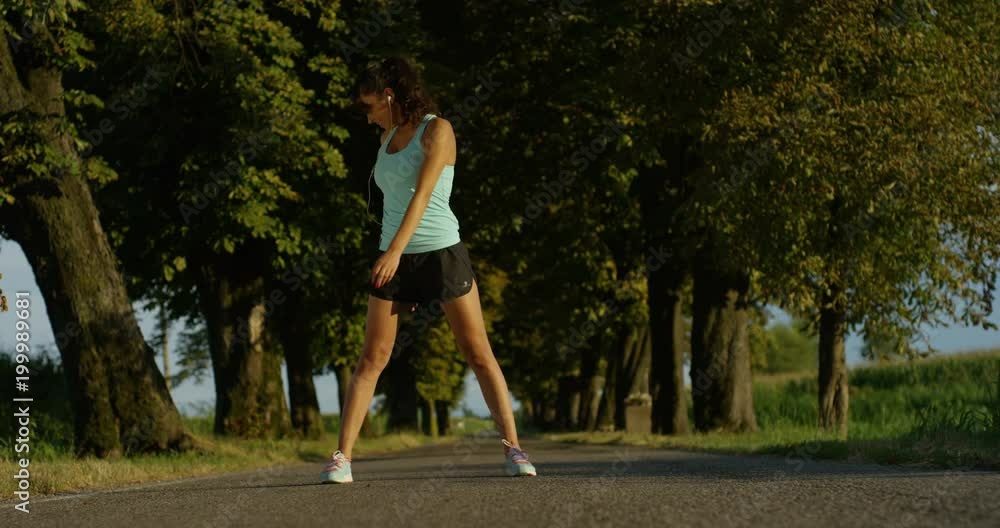 a happy girl fit relaxed jogging and running in a street with trees and nature, using headphones for music and run slow in sunset. concept of happiness for sports and fitness relaxation in nature a happy girl fit relaxed jogging and running in a street with trees and nature, using headphones for music and run slow in sunset. concept of happiness for sports and fitness relaxation in nature