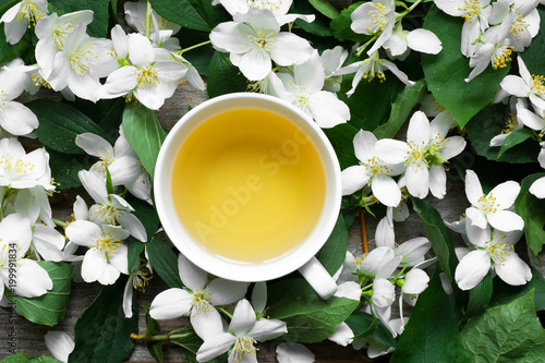 Cup of green jasmine tea on jasmine flowers background