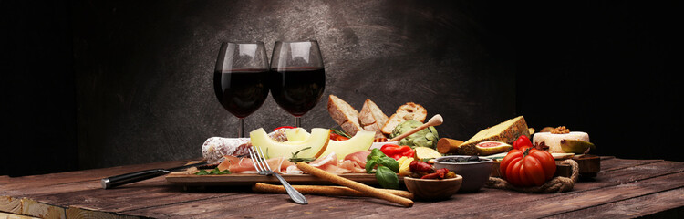Italian antipasti wine snacks set. Cheese variety, Mediterranean olives, pickles, Prosciutto di Parma with melon, salami.