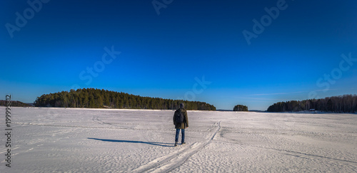 Falun - March 31, 2018: Traveler hiking on the frozen lake at Framby Udde near the town of Falun in Dalarna, Sweden photo