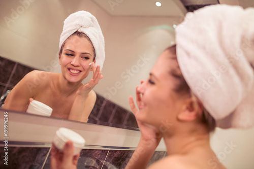 Woman applying facial cream on her face