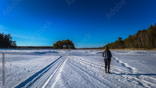 Falun - March 31, 2018: Traveler hiking on the frozen lake at Framby Udde near the town of Falun in Dalarna, Sweden photo