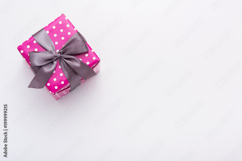 Hands holding wrapped gift box with colored ribbon as a present for Christmas, new year, mother's day, anniversary, birthday, party,  on white background, top view. Present for a colleague at work.