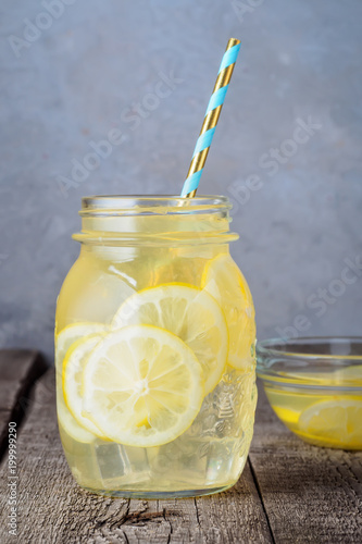 Coctail jar of lemonade and ice cubes crumbs on a wooden table background