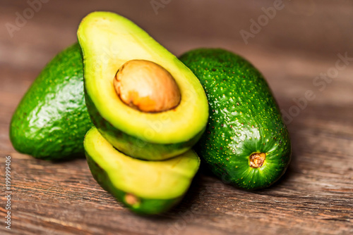 Avocados cut and whole on a wooden background