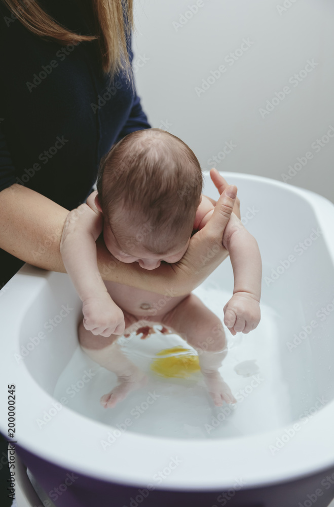 Ταπετσαρία Unrecognizable newborn girl in the bathtub held by her mother while washing her