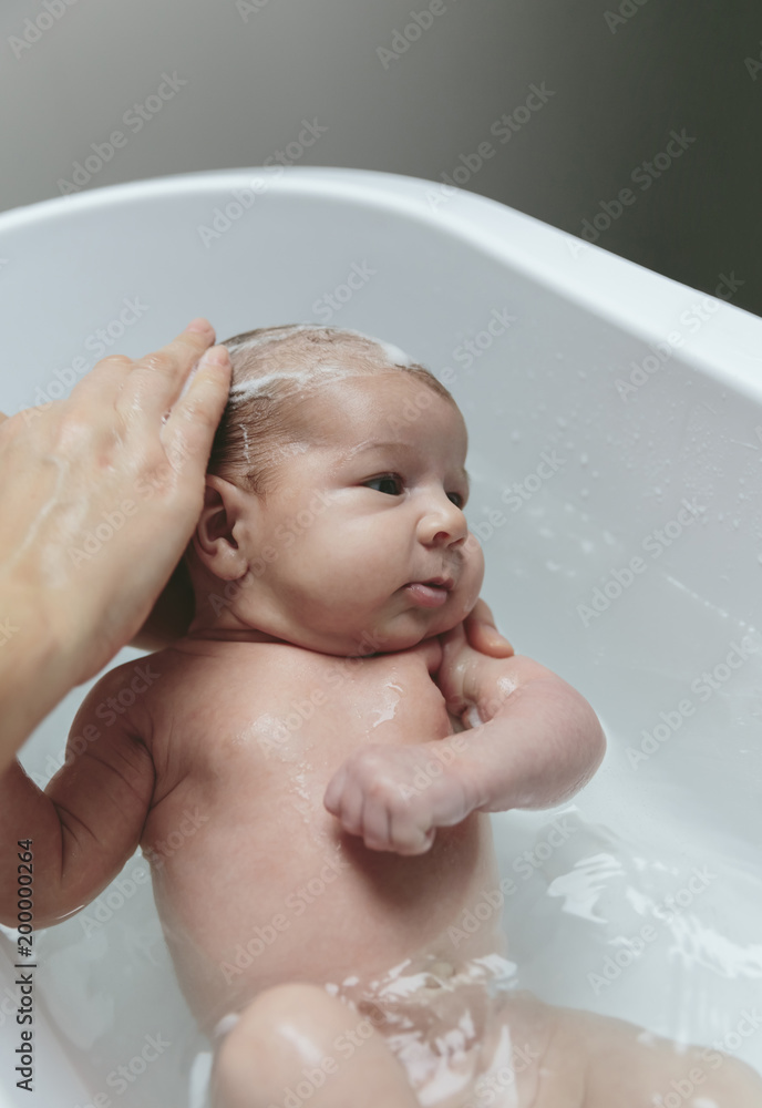 Portrait of relaxed newborn girl in the bathtub with her mother washing her hair Portrait of relaxed newborn girl in the bathtub with her mother washing her hair