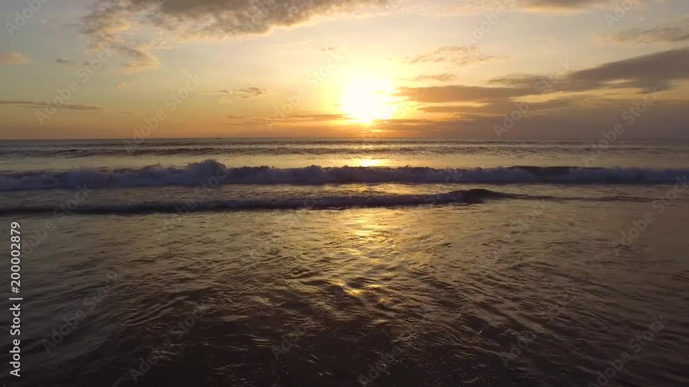 Glide shot towards sunset over beach and ocean waves Glide shot towards sunset over beach and ocean waves