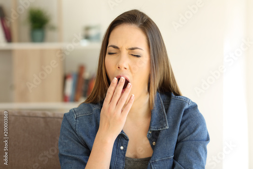 Tired woman yawning covering mouth
