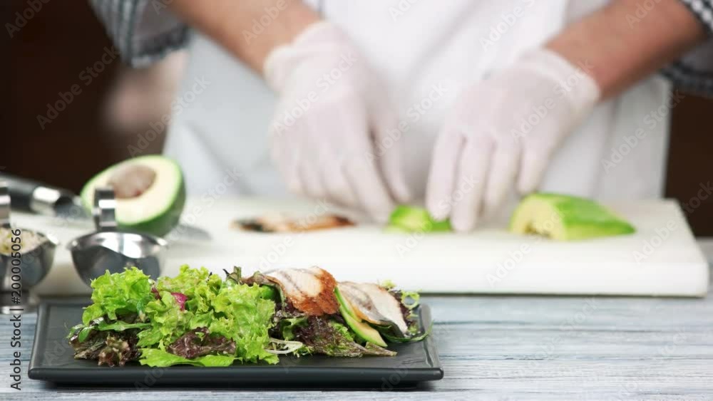 Hands of chef making salad. Lettuce, smoked eel and avocado. Hands of chef making salad. Lettuce, smoked eel and avocado.