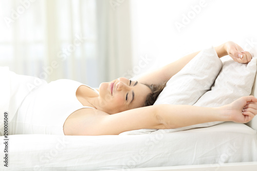 Woman stretching arms in the moring on the bed
