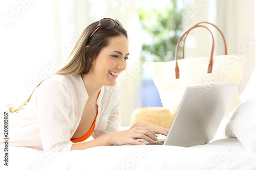 Woman using a laptop on a bed on summer vacations
