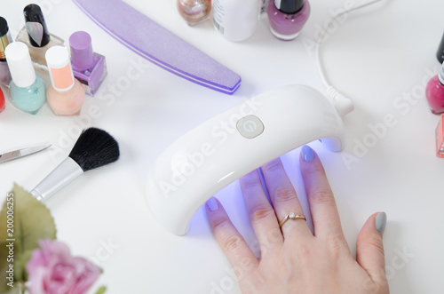 Woman using UV light dryer. Manicure  spa salon concept.