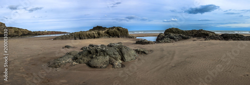 Panoramic view of St Cyrus beach with rocks, sea and house on the cliff on blue sky background. Aberdeenshire, Scotland, United Kingdom. April 2018.