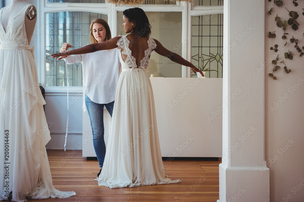Female fashion designer taking measure of woman Female fashion designer taking measure of woman