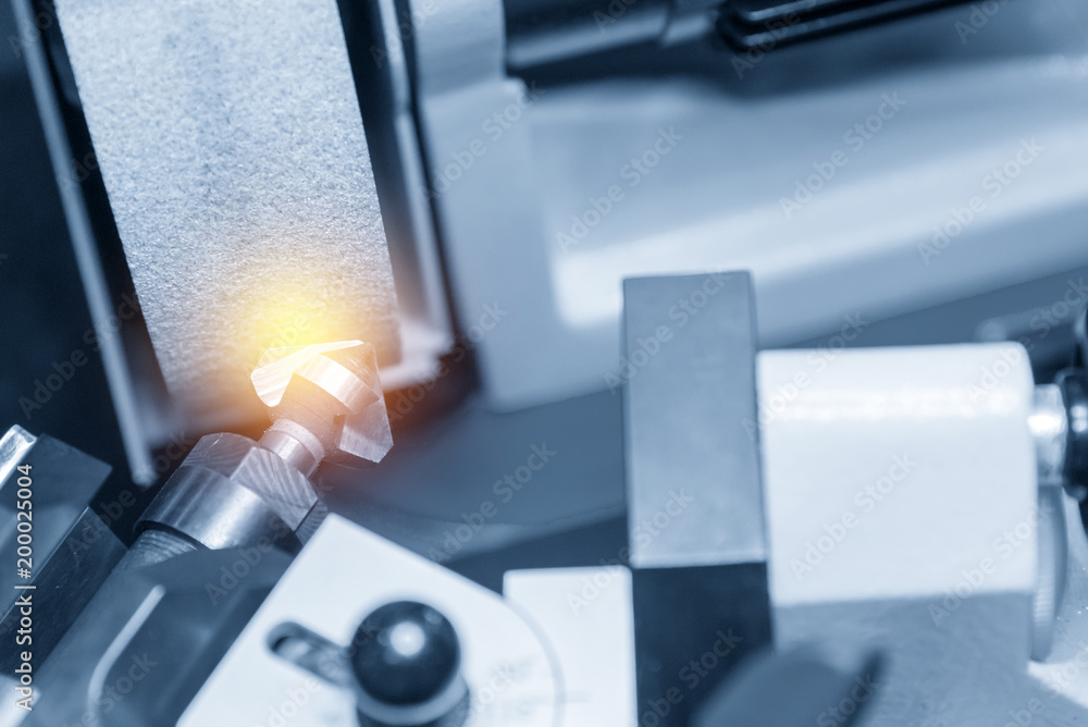 The chamfer tool sharpening at grinding machine in the light blue scene with lighting effect. The chamfer tool sharpening at grinding machine in the light blue scene with lighting effect.