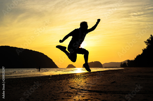 man traveler jumping on the beach when sunrise on vacation.silhouette concept.
