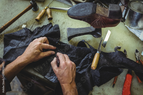 Shoemaker cutting a piece of material photo