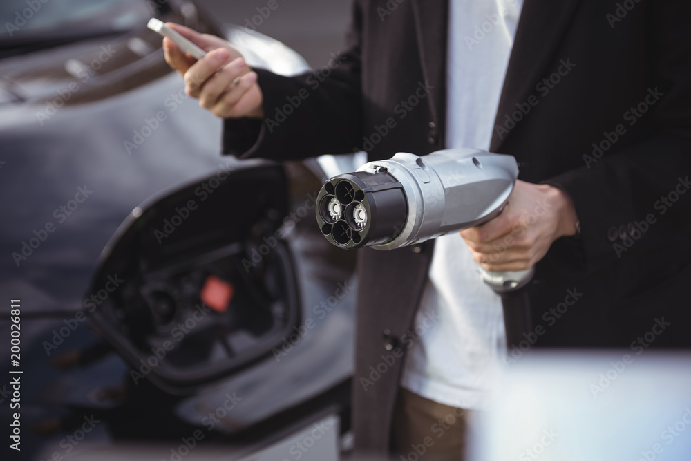 Man using mobile phone while holding car charger Man using mobile phone while holding car charger