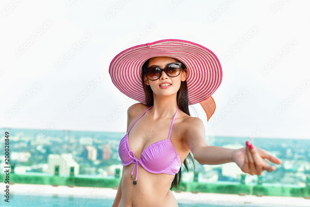 Swimsuit Concept. Beautiful girl wearing pink swimsuit. Beautiful girl in swimwear is relaxing at the swimming pool. Independent living sexy woman at the city center pool.