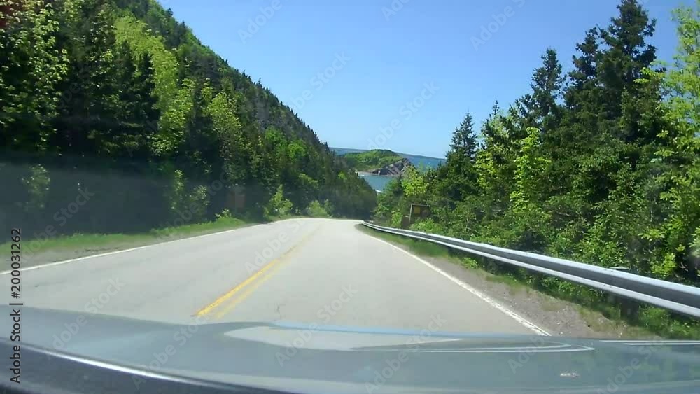 Vehicle drives down hill and around corners to reveal the ocean. Shot from the dash of a vehicle driving on the Cabot Trail on Cape Breton in Nova Scotia, Canada. Vehicle drives down hill and around corners to reveal the ocean. Shot from the dash of a vehicle driving on the Cabot Trail on Cape Breton in Nova Scotia, Canada.