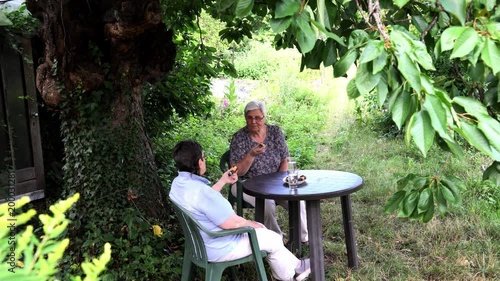 Senior ladies sitting in the garden under a tree enjoying coffee and cake photo