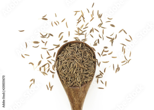 Cumin seeds in wooden spoon on a white background. Top view.